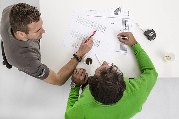 Stafdeling medewerkers aan tafel met bouwtekening