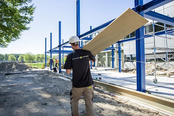Hillen en Roosen timmerman met houten plaat op nieuwbouw bouwput